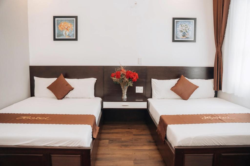 two beds in a room with a vase of flowers at Sunna Hotel in Da Nang