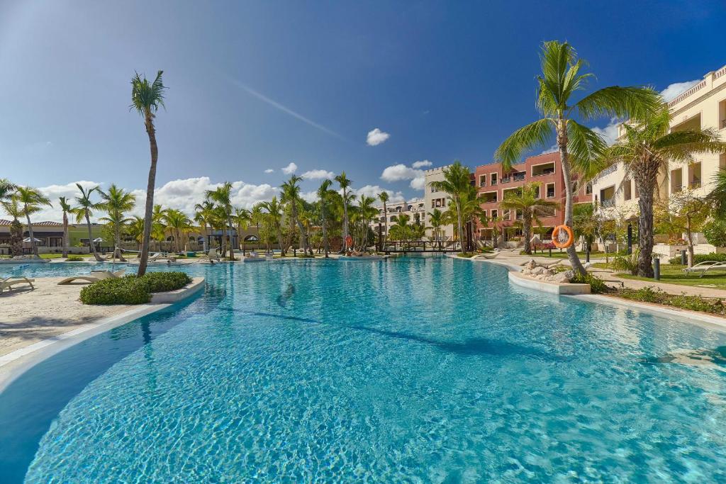 una gran piscina con palmeras y edificios en Beautiful apartment with pool view, en Punta Cana