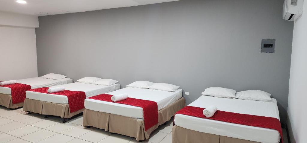 a room with three beds with red and white sheets at Hotel El Dorado in La Ceiba