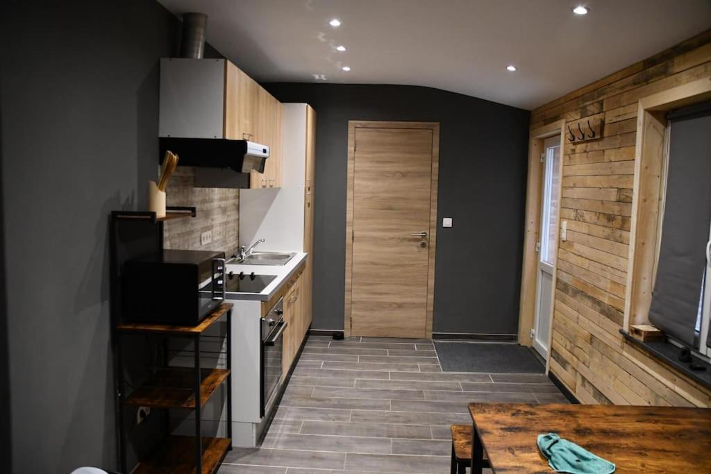 uma cozinha com um fogão, um lavatório e uma mesa em Logement in wood (400 mètres de Pairi Daiza) em Bolignies