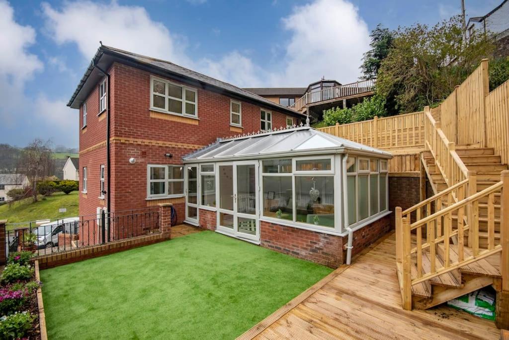 a house with a conservatory and a lawn at BROOK HOUSE 4a in Llangollen