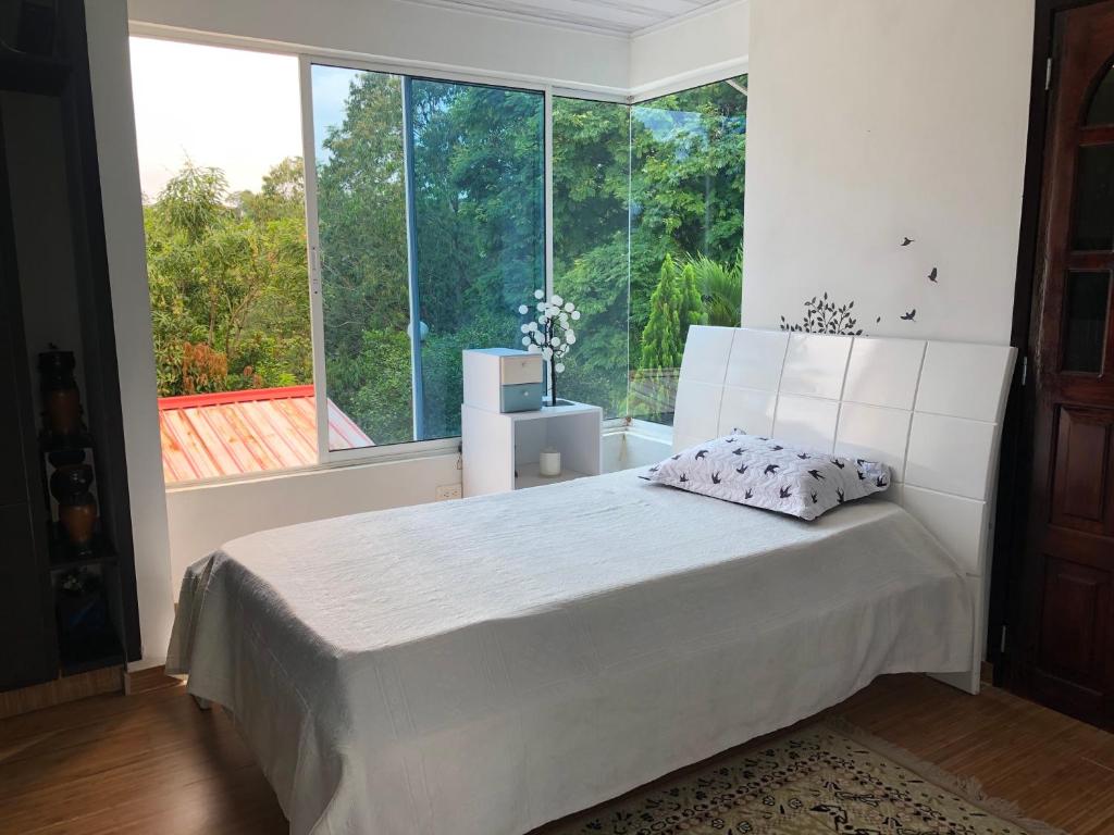 a bedroom with a white bed and a large window at Aventurina in Jamundí