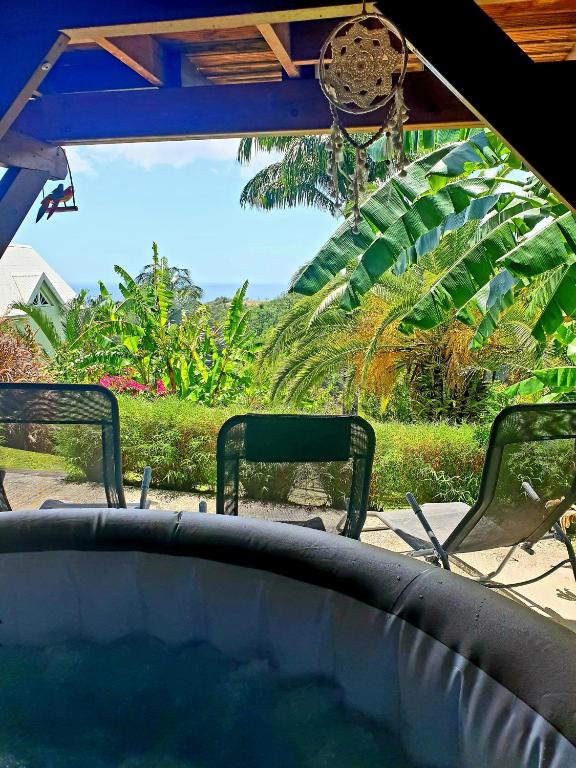 two chairs and a pool with a view of a garden at Gîte 4 étoiles, la Vieille Sucrerie St Claude Guadeloupe, Jacuzzi Spa privatif, vue exceptionnelle sur la mer des Caraïbes in Basse-Terre