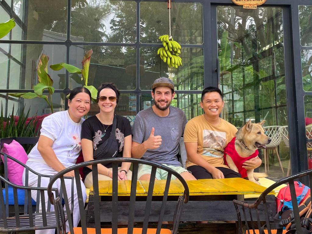 a group of people sitting at a table with a dog at Eden House & Coffee Con Dao in Con Dao