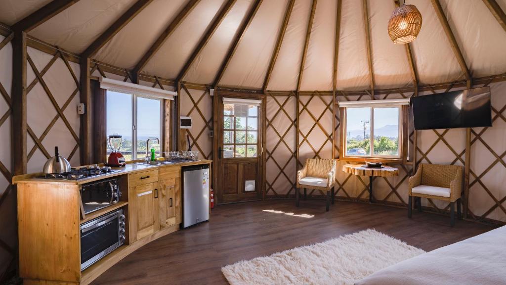 a yurt with a kitchen and a table and chairs at Domos Anulen in Puerto Varas