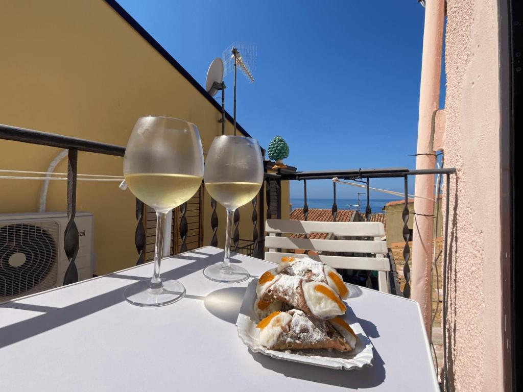 una mesa con 2 copas de vino blanco en el balcón en RockSea Apartments Attic Floor en Cefalú