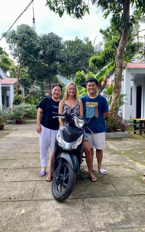 a group of people standing next to a motor scooter at Eden House & Coffee Con Dao in Con Dao