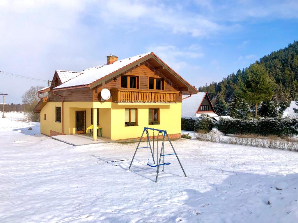 a yellow house with a swing in the snow at Chata Ski Chopok in Belá
