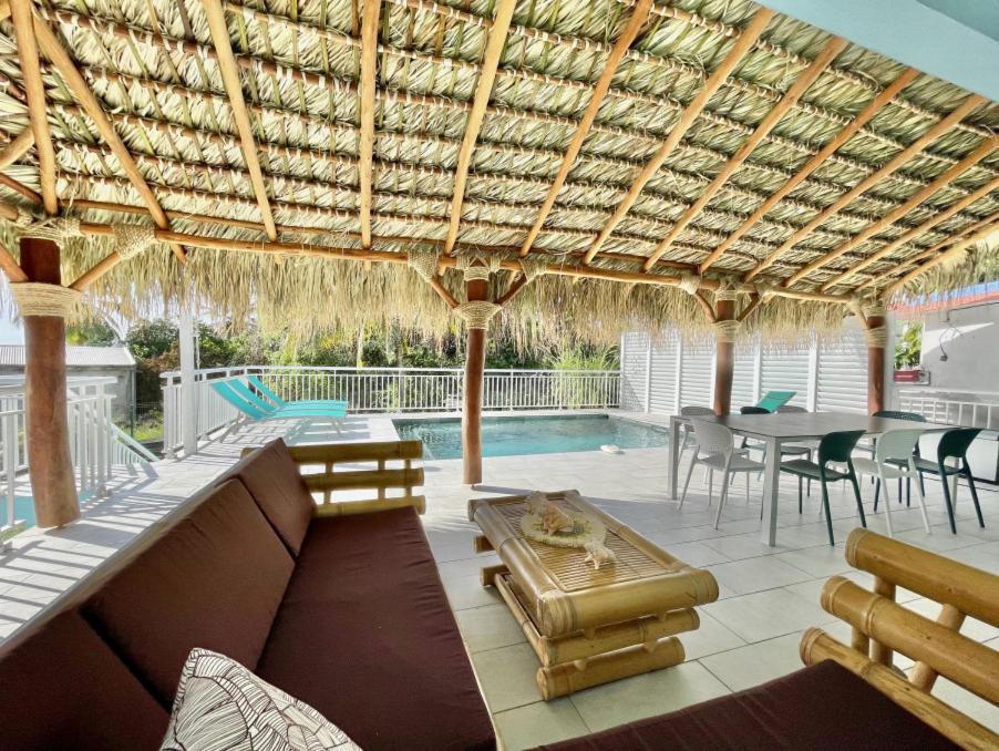 une terrasse avec un canapé, une table et une piscine dans l'établissement Villa en bord de mer, vue mer au Diamant, au Diamant