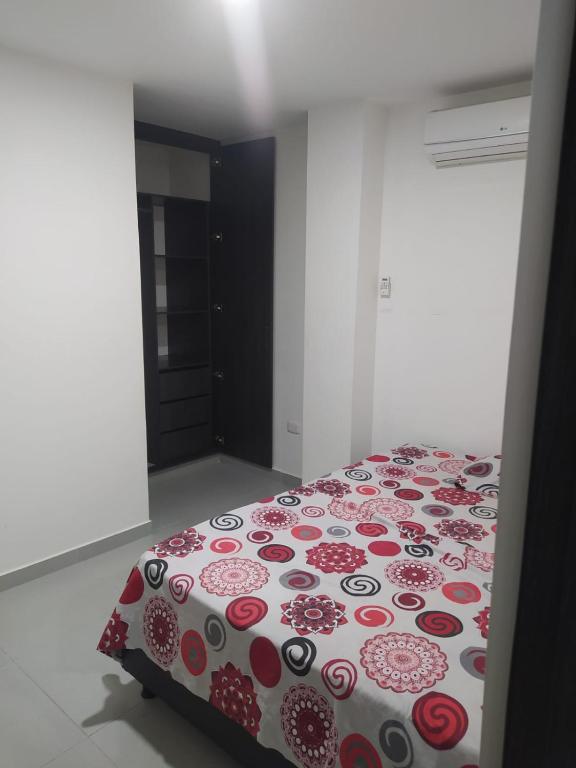 een slaapkamer met een bed met een rood en wit dekbed bij Hermoso aparta estudio con Aire Acondicionado en un primer piso Cerca al Hospital de Neiva in Neiva