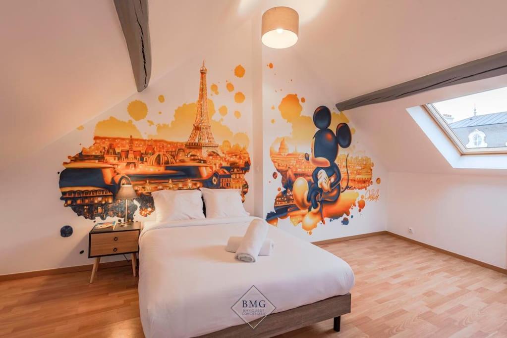 - une chambre avec un lit et un mur orné d'une fresque murale dans l'établissement Disney House, à Chessy