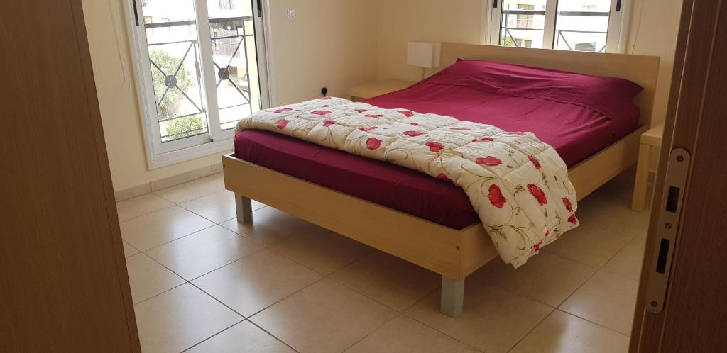 a bedroom with a bed with a purple comforter and a window at Mazotos Panoramic Village in Mazotos