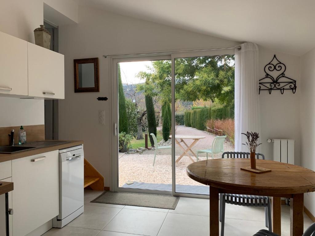 eine Küche mit einem Tisch und eine Tür zu einer Terrasse in der Unterkunft Chèvrefeuille gîte & chambre d'hôtes in Moltig les Bains