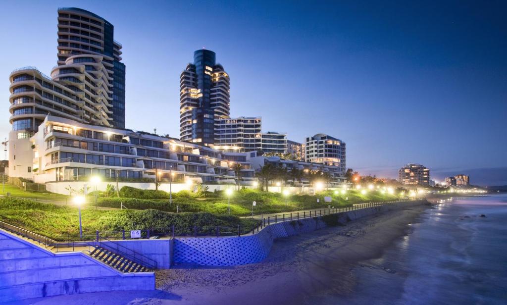 una città di notte con una spiaggia e edifici di The Pearls of Umhlanga - Ocean view Apartments a Durban