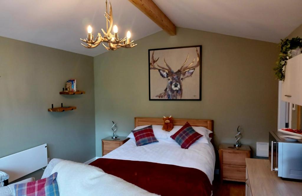 a bedroom with a bed with a deer on the wall at Erraid Lodge in Fort Augustus