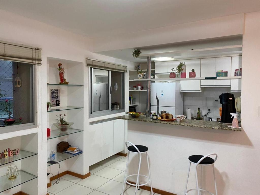 una cocina con armarios blancos y 2 taburetes en Miniduplex bem localizado, en Brasilia