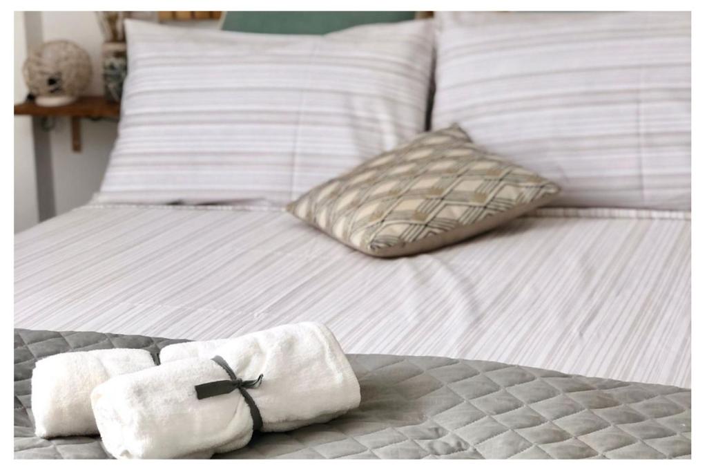 uma cama branca com almofadas brancas e toalhas em Dèpendance immersa tra gli ulivi em Cologna