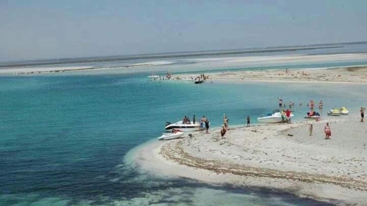 un grupo de personas en una playa con barcos en el agua en Belle appartement vue de mer en Zarzis