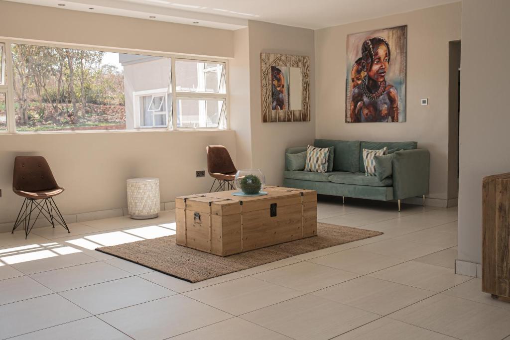 Gletwyn Boutique Guesthouse في هراري: غرفة معيشة مع أريكة خضراء وطاولة