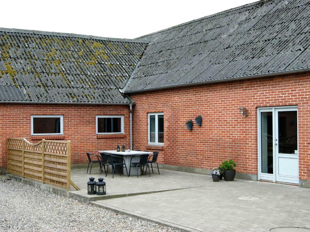 ein Backsteingebäude mit einer Terrasse mit einem Tisch in der Unterkunft Vestervang Bed & Breakfast in Vildbjerg