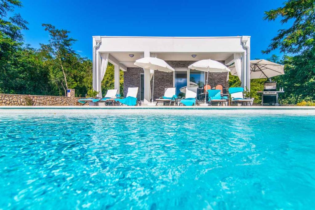 - une piscine avec des chaises et des parasols à côté d'une maison dans l'établissement Villa Sofia Santalezi, à Santalezi