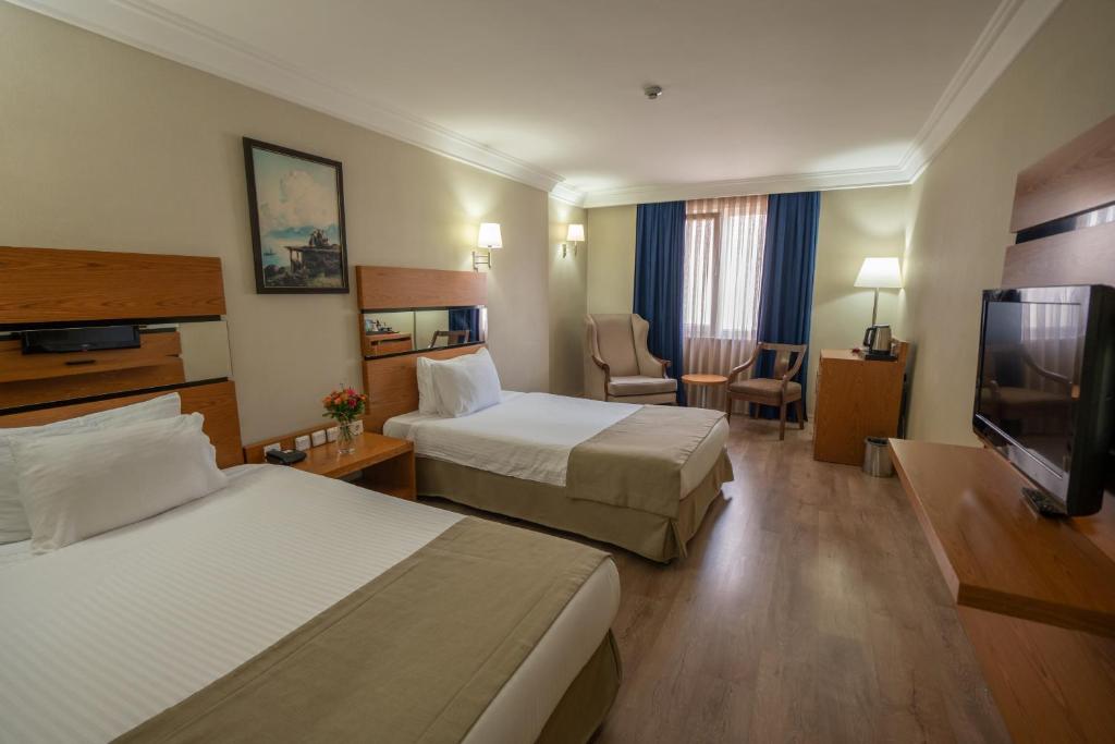 a hotel room with two beds and a flat screen tv at The Green Park Taksim in Istanbul