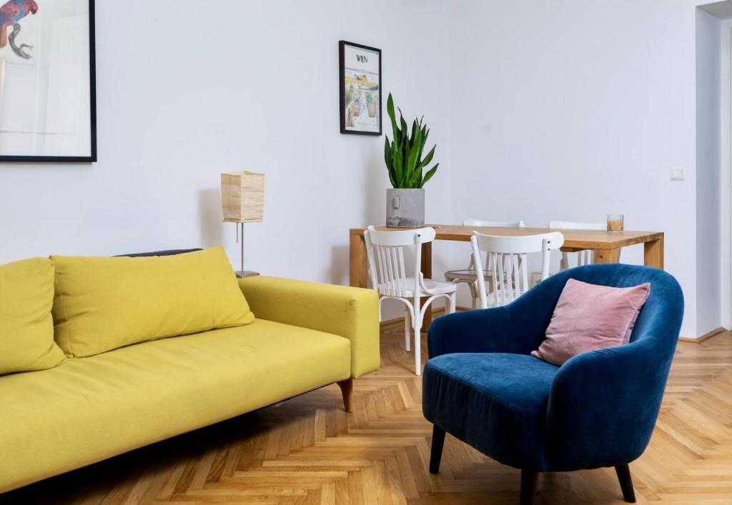 un salon avec un canapé jaune et un fauteuil bleu dans l'établissement Altbauschatz am Alsergrund, Nähe Innere Stadt, à Vienne