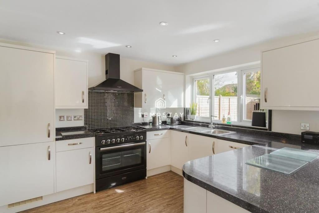 a kitchen with white cabinets and a black stove top oven at Spacious 5 bed Sunninghill with driveway parking in Ascot