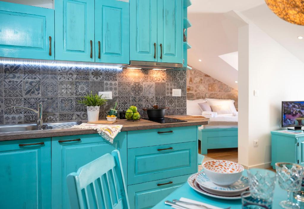 a kitchen with blue cabinets and a table at Imperia - Chic! place with balcony in Dubrovnik