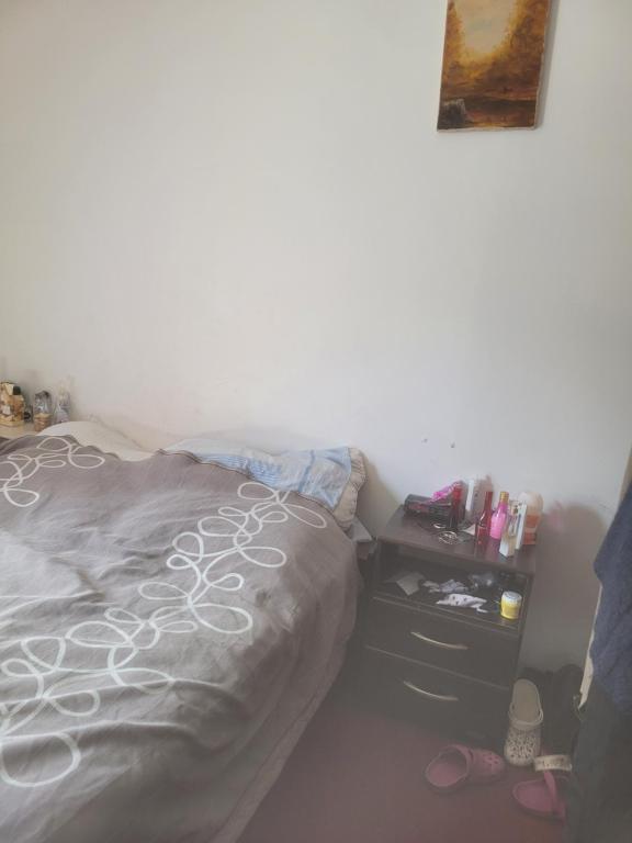 1 dormitorio con 1 cama y mesita de noche con zapatos en Habitacion privada en casa en Ushuaia
