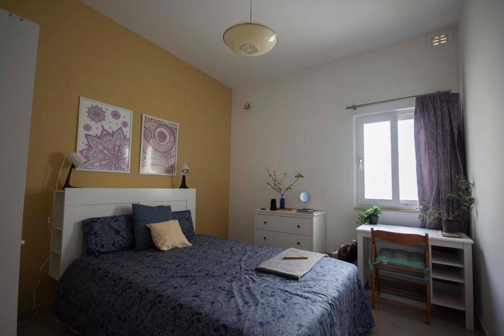 una camera con letto, scrivania e finestra di HomeStay @ Viewpoint St Julians a San Giuliano