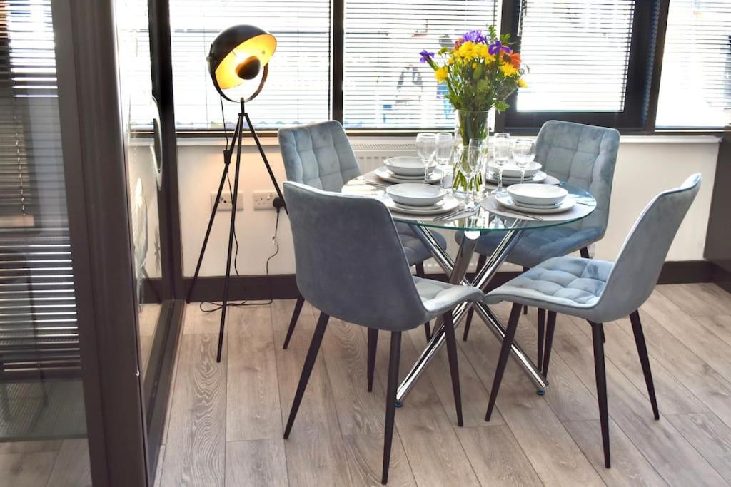 stół jadalny z krzesłami i stół z kwiatami w obiekcie The Copperfield Apartment - Broadstairs Central - By Goldex Coastal Breaks w mieście Kent