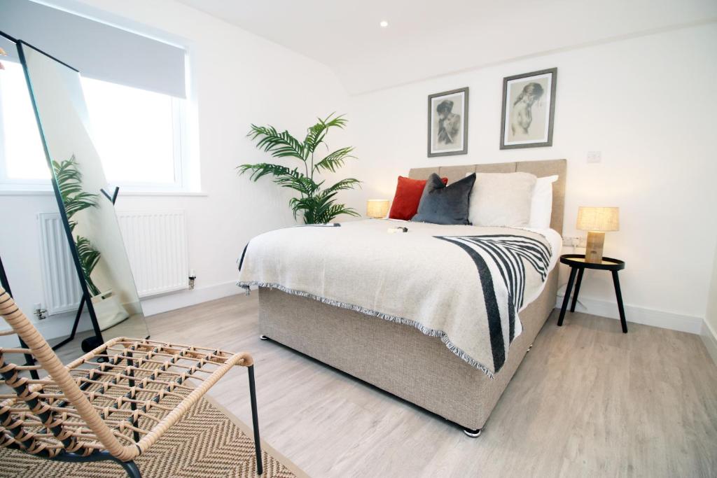 a white bedroom with a bed and a plant at Long stay offer - Stylish 1 bed flat with parking in Bristol