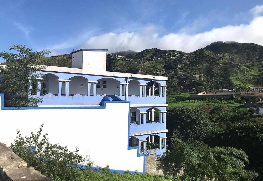 un edificio blanco en una colina con montañas al fondo en Djabraba's Eco-Lodge, en Vila Nova Sintra