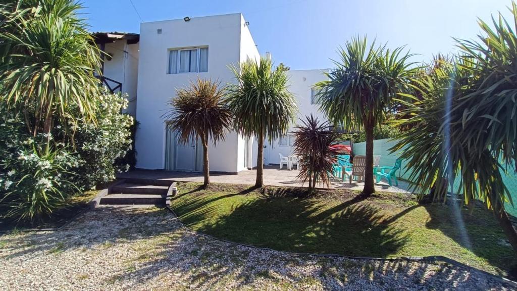 une maison avec des palmiers devant elle dans l'établissement Casa en Bosque Peralta Ramos, à Mar del Plata