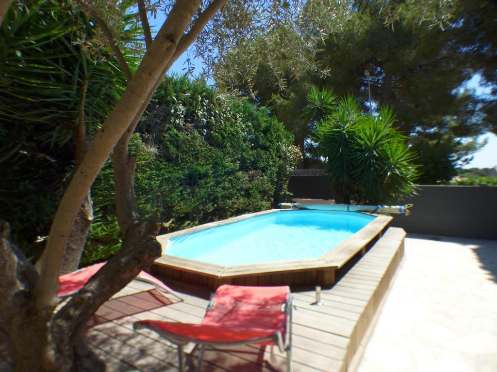 basen z 2 krzesłami i czerwonym krzesłem w obiekcie Piscine chauffée climatisation Wifi w mieście Six-Fours-les-Plages