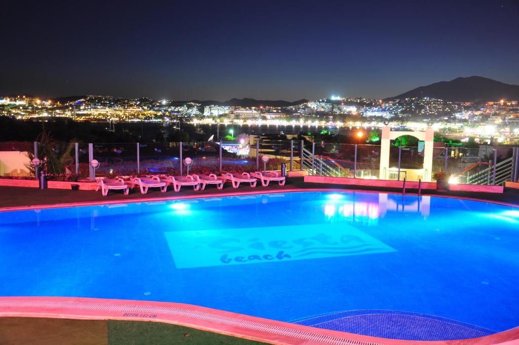 a pool with a view of a city at night at Siesta Beach Apartment in Gümbet