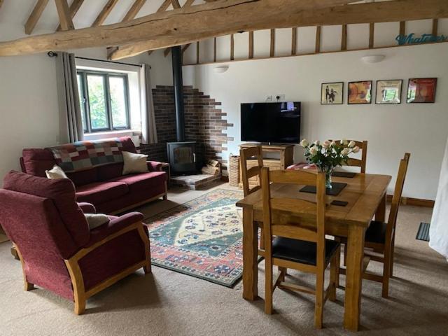 - un salon avec une table, des chaises et un canapé dans l'établissement Wood Farm Barn, à Laxfield