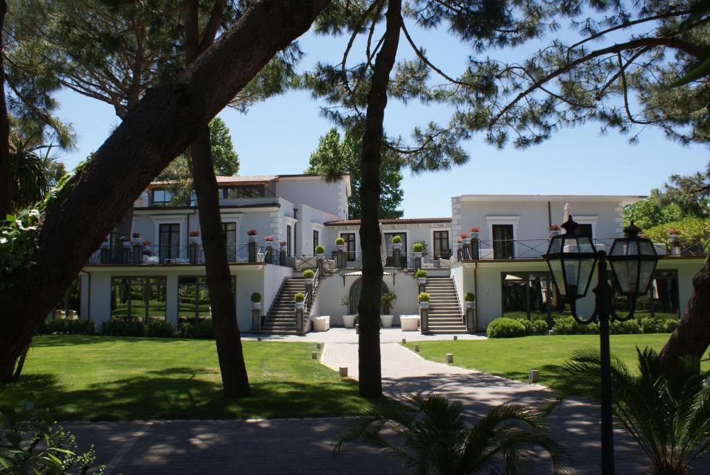a large white house with trees in the foreground at Villa Minieri Resort & SPA in Nola
