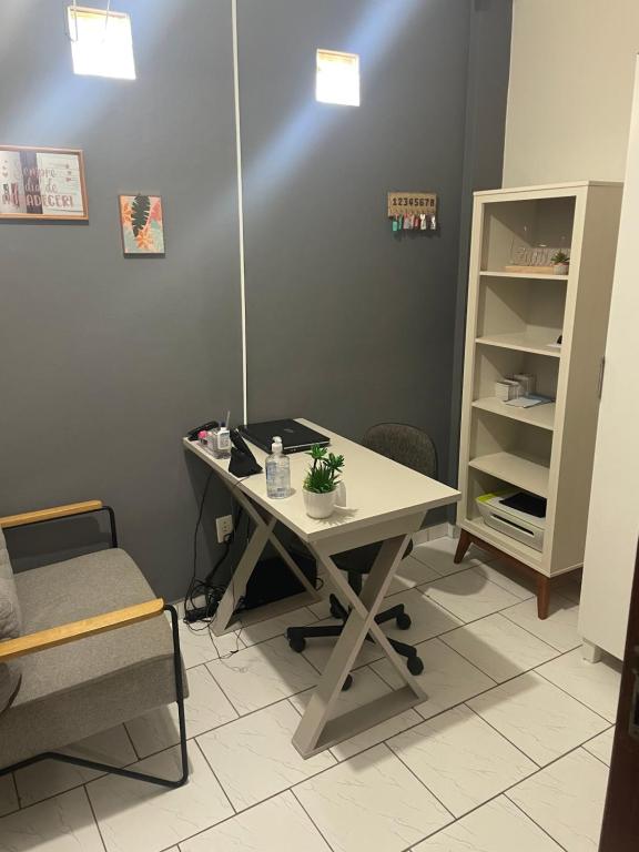 a office with a desk and a chair and a shelf at Pousada carioca in São João da Barra