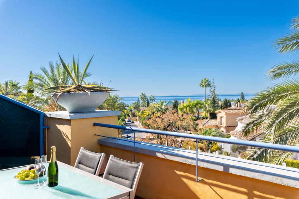 d'un balcon avec une table, des chaises et des palmiers. dans l'établissement Bahia de Marbella - 3 bedroom beach apartment with sea view, à Marbella