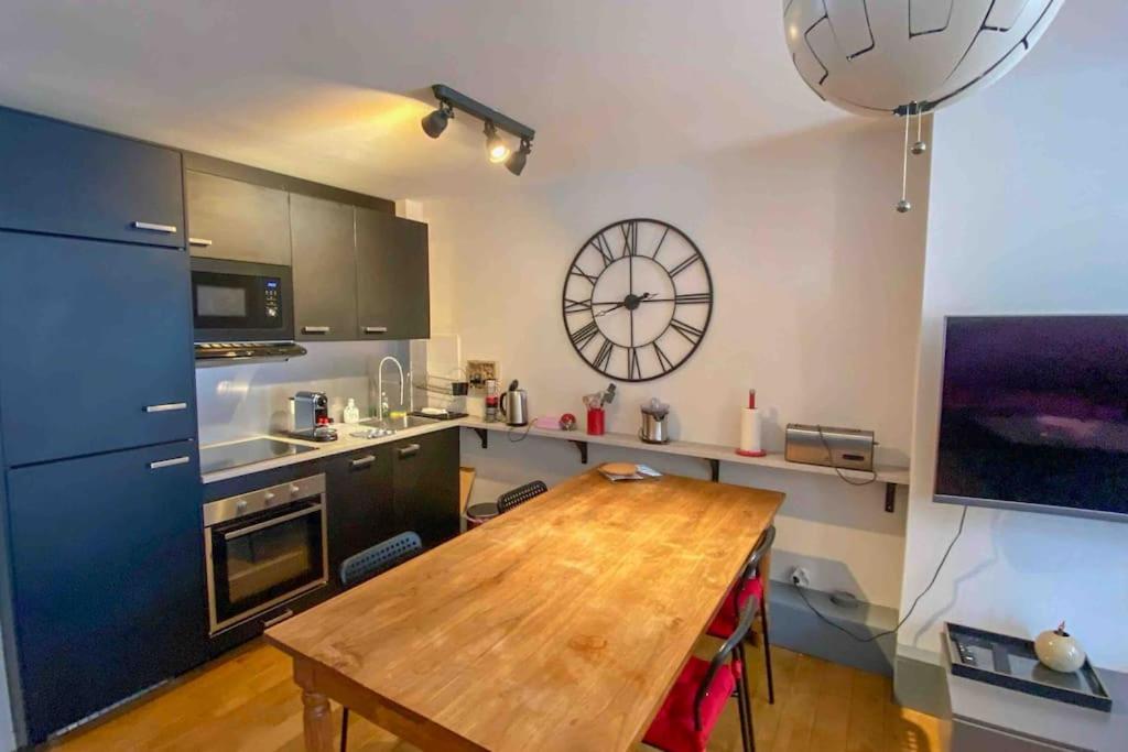eine Küche mit einem Holztisch und einer Uhr an der Wand in der Unterkunft Bel appt 42m² au cœur de Trouville 2mns de la mer in Trouville-sur-Mer