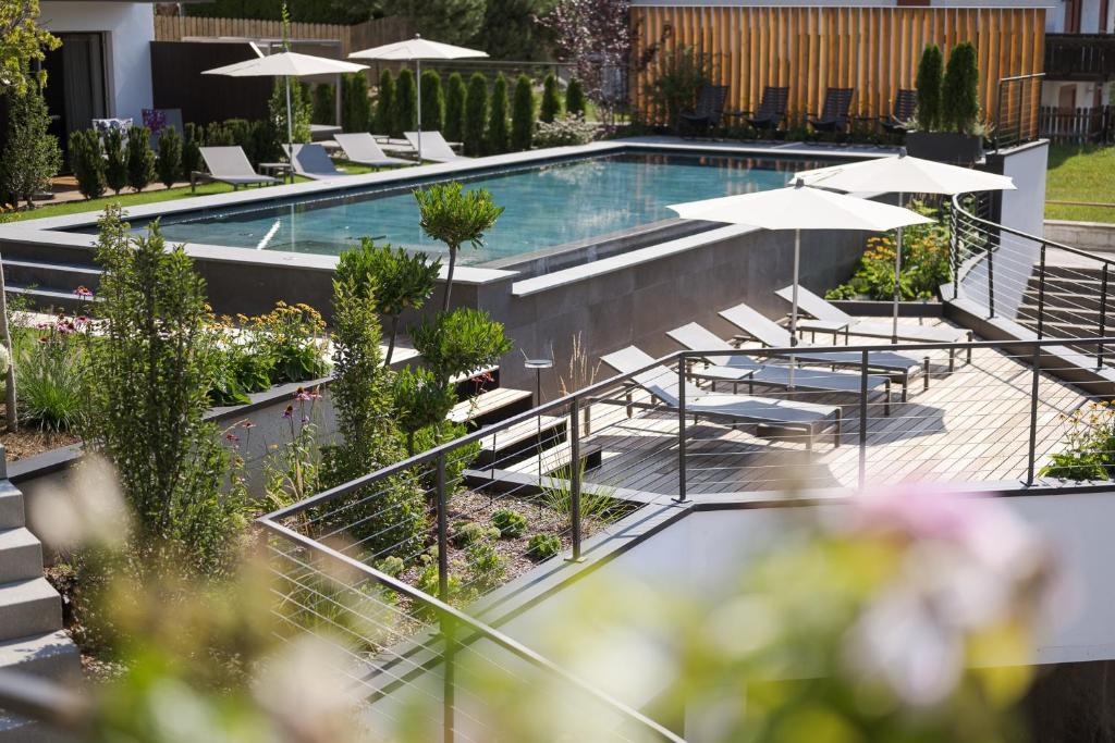 a swimming pool with lounge chairs and umbrellas at Hotel Salten in Avelengo