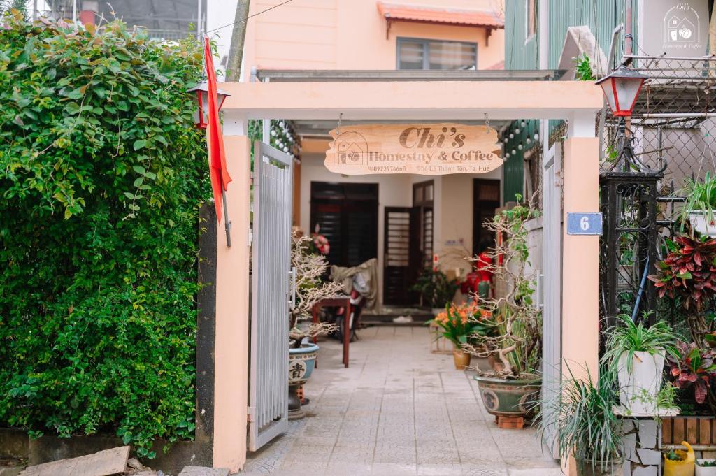 una entrada a un restaurante con plantas y un cartel en Chi's Homestay & Coffee, en Hue