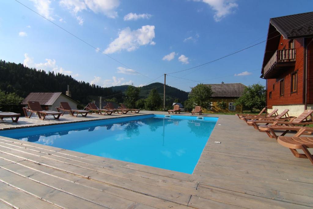 een groot zwembad met stoelen en een gebouw bij Карпатська садиба in Plavie