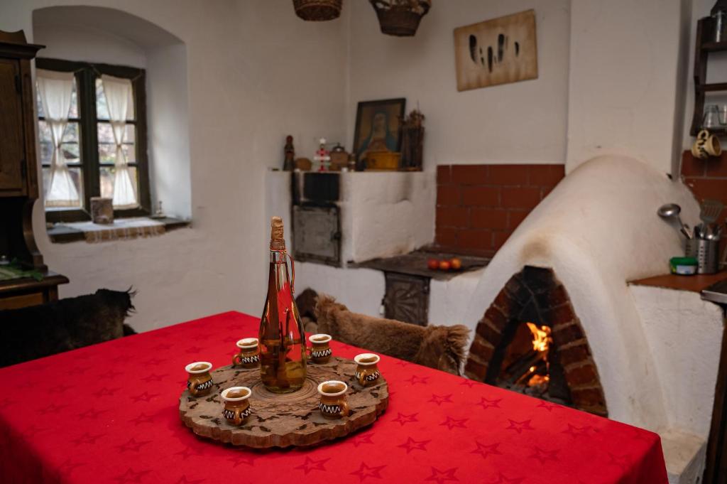 Casa Sub Magrin في Satu Bătrîn: غرفة معيشة مع موقد مع قماش الطاولة الحمراء