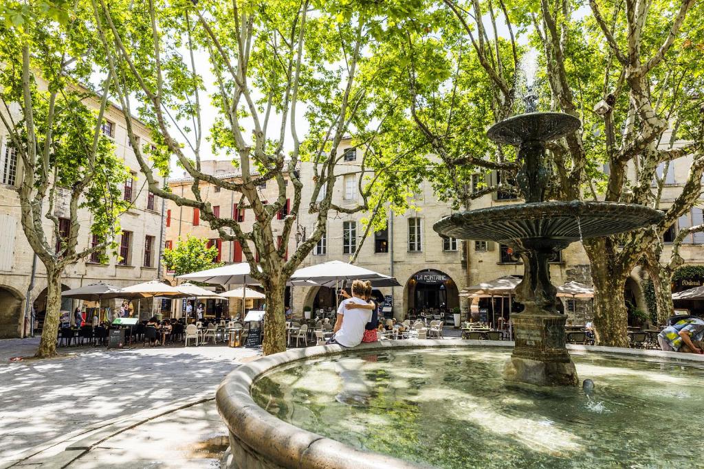 a woman is standing next to a fountain at Le 6 Bis by Les Cailloux Dorés in Uzès