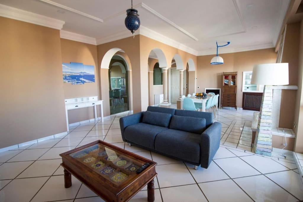 Casa Paradiso - sea view downtown penthouse في نابولي: غرفة معيشة مع أريكة زرقاء وطاولة