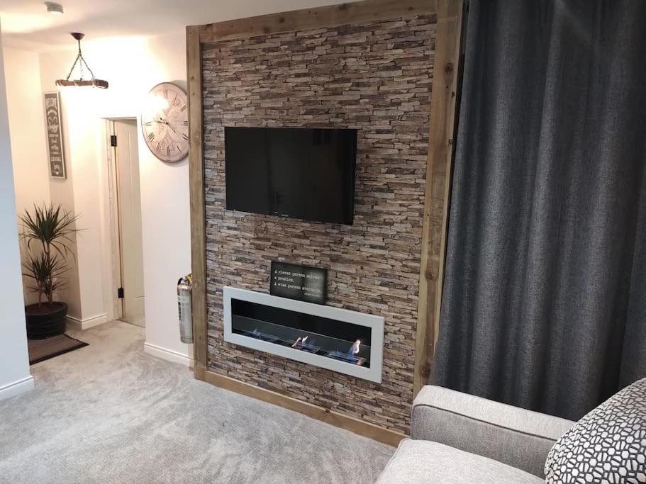 a living room with a brick wall with a flat screen tv at Silver Sovereign in Banbridge