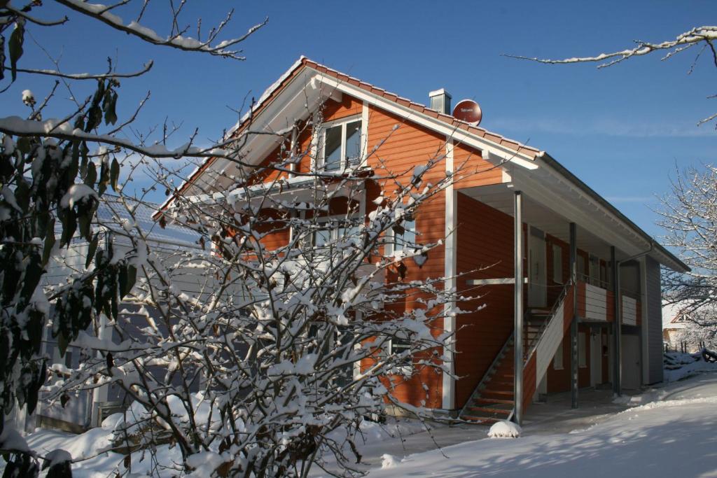 ein schneebedecktes Haus mit einem Baum im Vordergrund in der Unterkunft Bella Natura in Loffenau